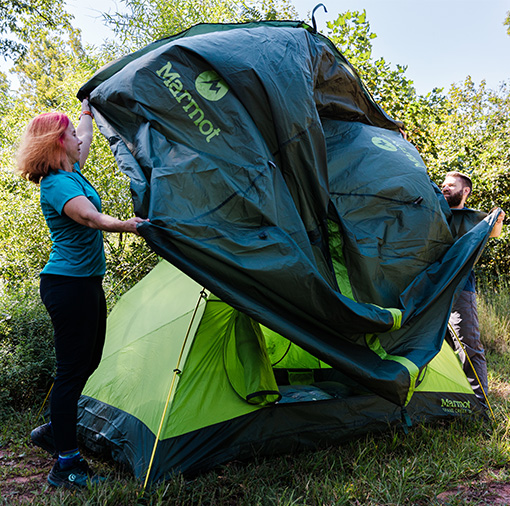 Two people pitching a tent outdoors
