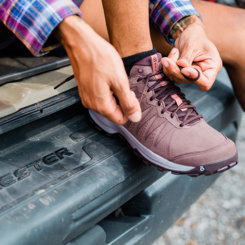 Woman tying up hiking shoes outdoors